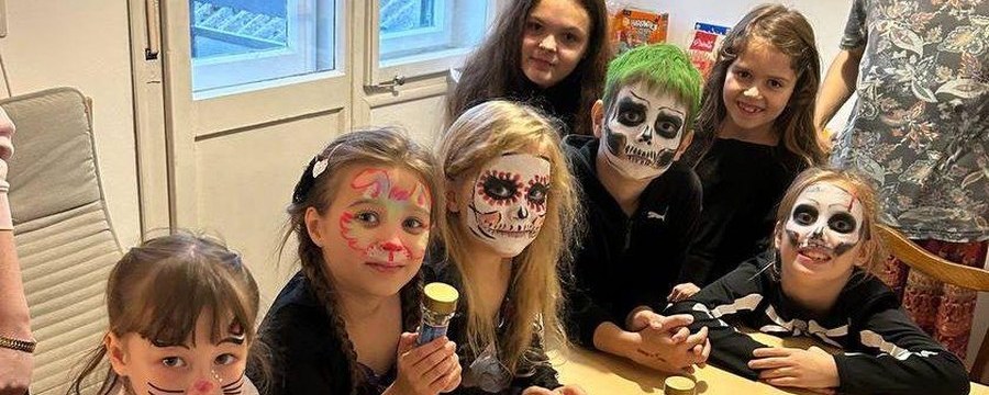 Дети с аквагримом-черепами за столом на Хеллоуине